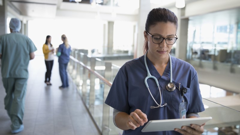 female doctor wearing a stethoscope and studing reports on tab 