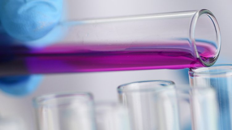 Medical researcher adding a chemical liquid to a test tube during their research in a medical laboratory