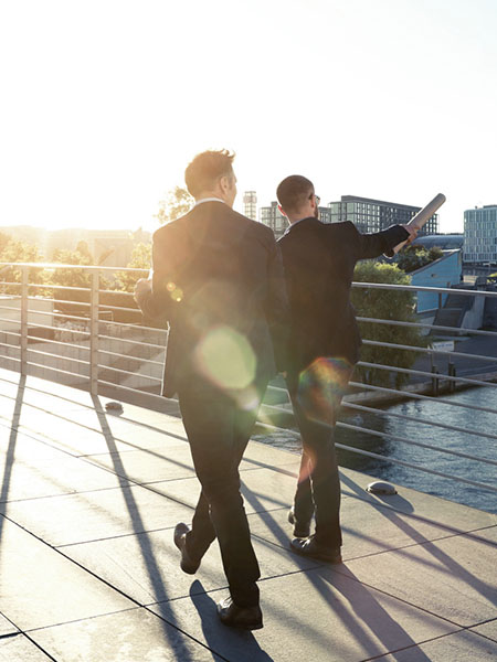 Two businessmen walking on a bridge by the river