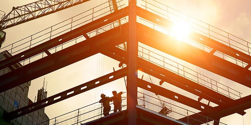 Construction workers silhouetted against the sun
