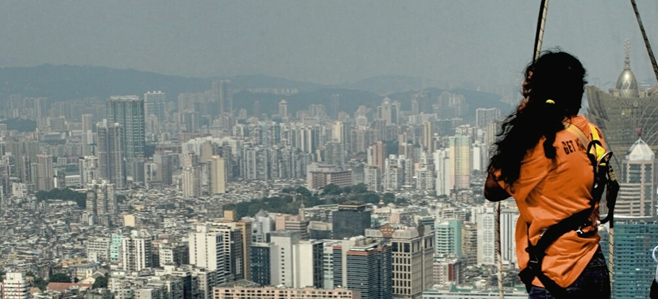 side view of woman bungee jumping at macau tower against cityscape