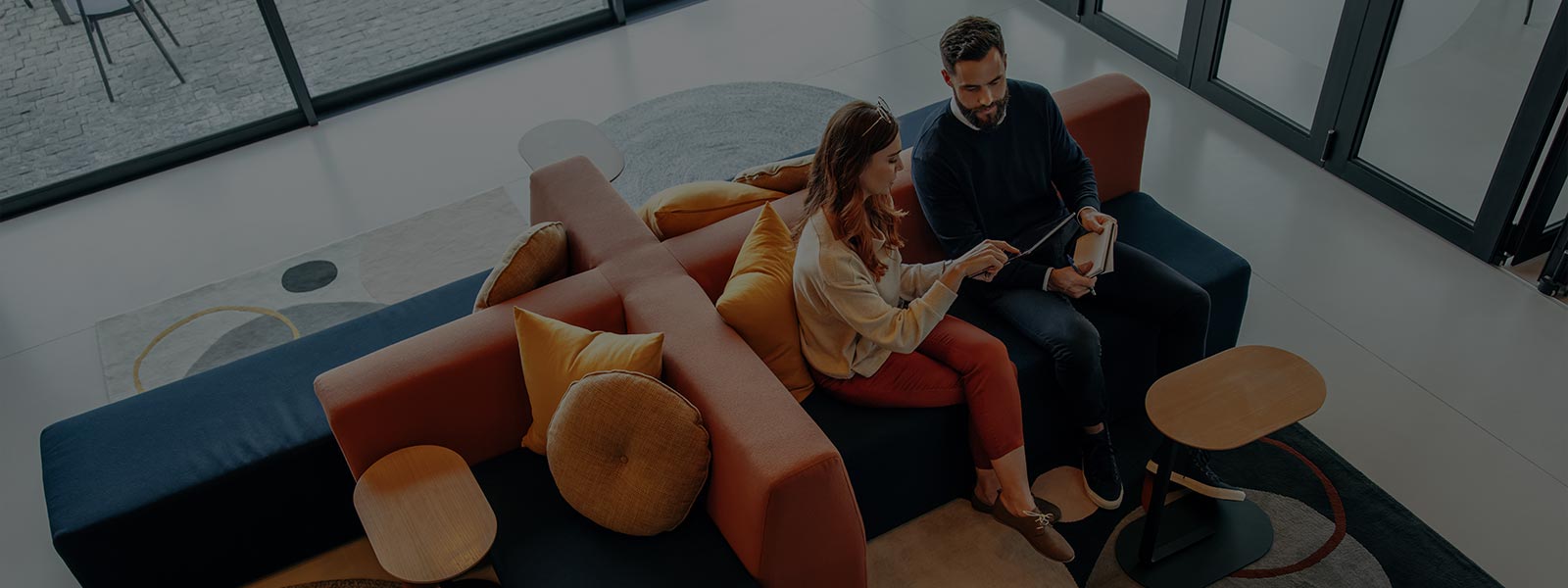 A man and women look something in mobile while sitting on Sofa