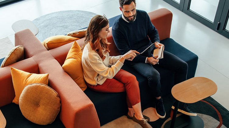 A man and women look something in mobile while sitting on Sofa