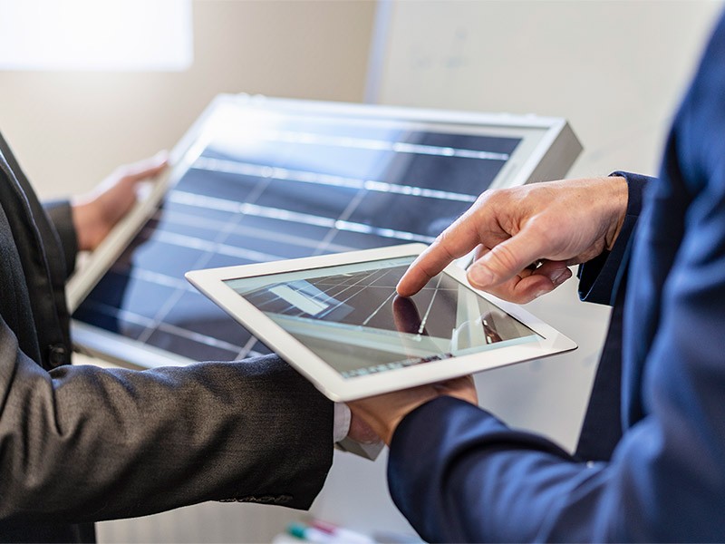 Close-up of two businessmen in office with solar cell and tablet