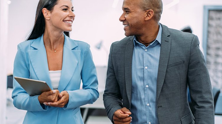 Male and female business colleagues in mentoring partnership discussing workplace strategies